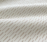 Close-up of off-white fabric with pale taupe elongated dash pattern, showing soft folds and subtle texture under natural light.