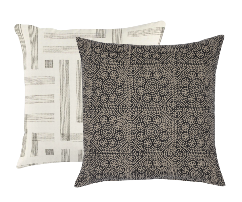 Two square pillows, one with a dense black floral dot pattern on a beige background, the other with a beige background and simple black linear geometric stripes.