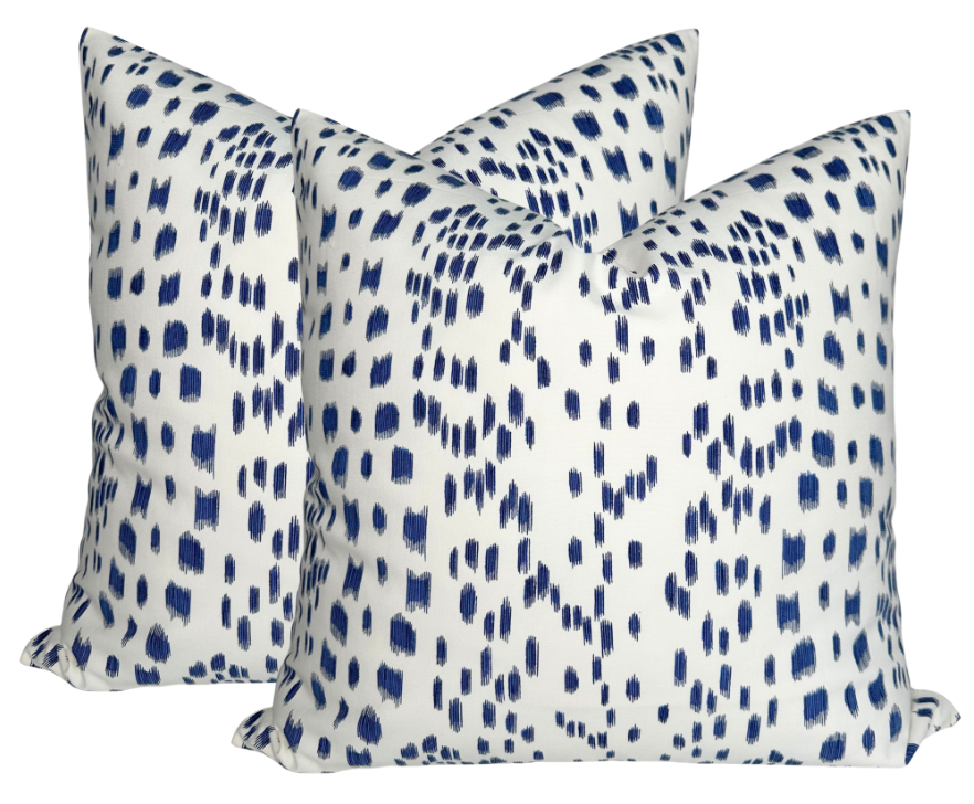 Two square pillows with a white background covered in scattered short navy blue brushstroke dots creating a textured pattern.