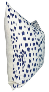 Rectangular pillow cover with a white background featuring irregular blue brushstroke patterns and plain beige fabric on the sides, shown at an angle.