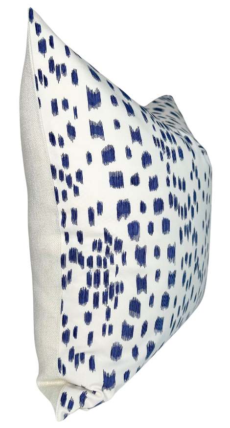Rectangular pillow cover with a white background featuring irregular blue brushstroke patterns and plain beige fabric on the sides, shown at an angle.