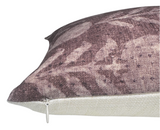 Close-up of a pillow cover featuring a muted berry-colored zinnia floral pattern with subtle leaves on textured fabric, contrasted with a plain off-white back and a small zipper.