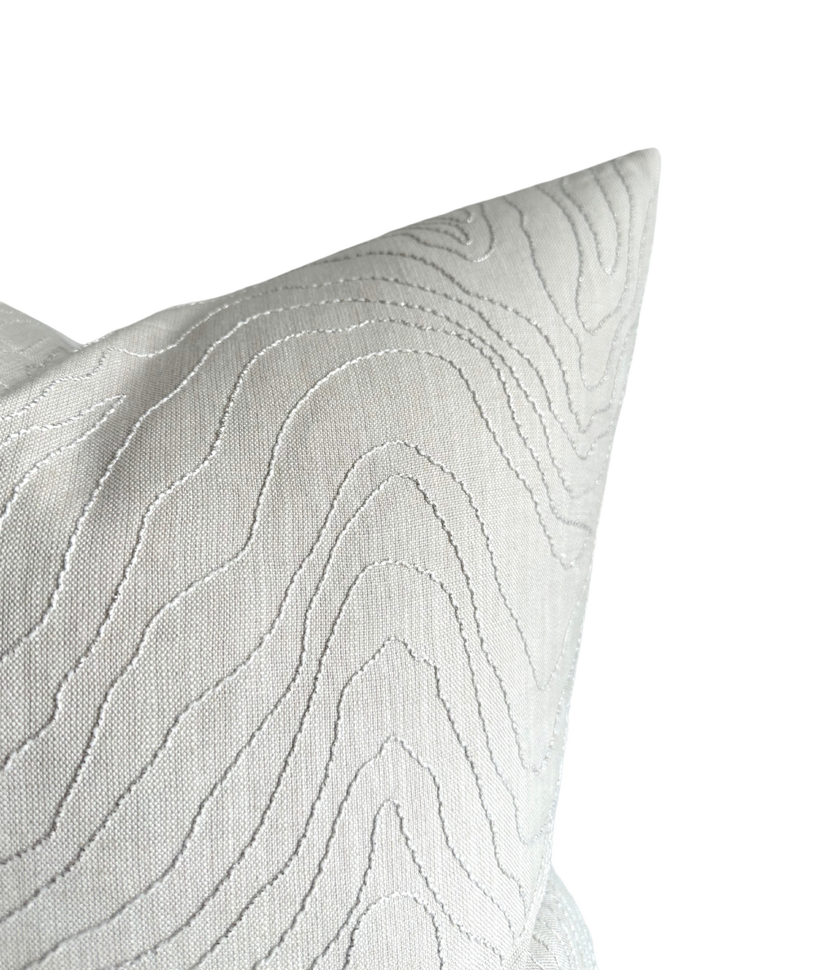 Close-up of a light oyster-colored pillow cover featuring subtle wavy embroidery creating a textured, flowing pattern on smooth fabric.