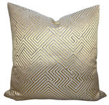 Golden velvet pillow cover with geometric maze pattern displayed on a dark couch
