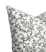 Square pillow cover with indigo vine floral print on natural beige fabric, featuring winding stems and detailed blossoms in a repeating pattern.