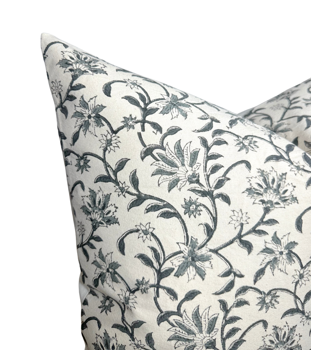 Square pillow cover with indigo vine floral print on natural beige fabric, featuring winding stems and detailed blossoms in a repeating pattern.