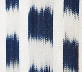 Close-up of indigo blue and white striped fabric with a blurred, ikat-inspired pattern on textured woven cotton.