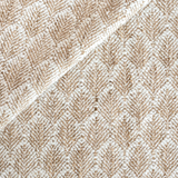 Close-up of textured fabric featuring a geometric floral pattern in natural beige and white tones, highlighting the raised woven fibers and subtle diagonal fold.
