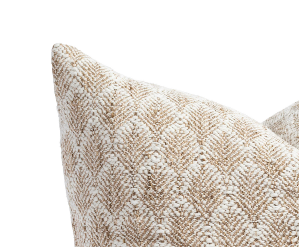 Close-up of a pillow corner with textured beige and white floral pattern woven in a natural fabric.