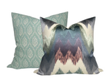 Two decorative pillows, one with a teal pattern of vertical oval leaf motifs and the other with an abstract zigzag gradient in shades of blue, gray, and mauve.