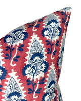 Corner of a pillow with a red background featuring a repeating pattern of stylized blue and white floral motifs within pointed oval shapes.