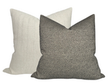 Two woven pillow covers, one in charcoal gray with a nubby texture in front and one in off-white with a subtle woven pattern behind it.