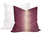 Two square pillow covers, one with a white background and subtle blush pink dots, the other in deep blush with a central textured gold stripe.