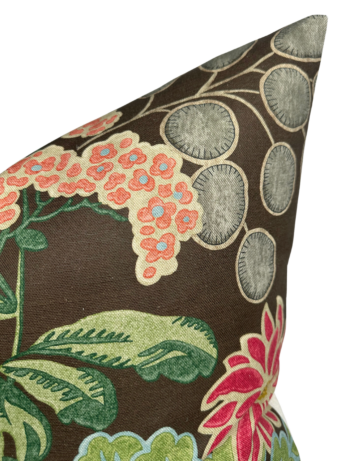 Close-up of a brown pillow cover with embroidered pastel coral flowers, green leaves, and beige circular patterns on textured fabric, showing a pointed corner.