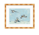 Fine art print depicting three pheasants in orange, blue, and black flying against a pale blue, loosely textured sky background, framed in light wood with white mat.