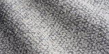 Close-up of a woven pillow cover fabric showing a dense pattern of small, irregular platinum-colored loops with subtle shading variations creating a textured effect.