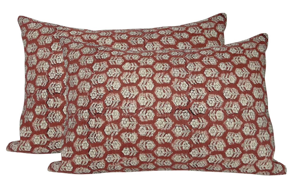 Two rectangular pillow covers with a repeating geometric floral pattern in muted cream on a deep reddish-brown saffron background.