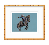 Painting of a cowboy riding a bucking horse against a muted blue background, framed by a golden bamboo-style frame with white matting.