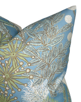 Close-up of a spa blue pillow cover featuring detailed white and green protea floral patterns with black-lined leaves and small white berry clusters.