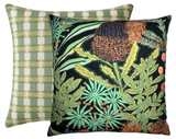 Two square pillows with distinct covers: front pillow has a vivid black background with detailed green and orange protea flower and leaf pattern; back pillow shows a green and white checkered pattern.