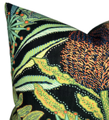Close-up of a pillow cover featuring intricate protea flower and foliage patterns in shades of green, orange, and blue on a black background.