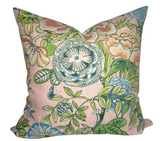 Square pillow cover with blush pink background featuring large, detailed floral patterns in green, blue, cream, and peach tones with leafy accents.