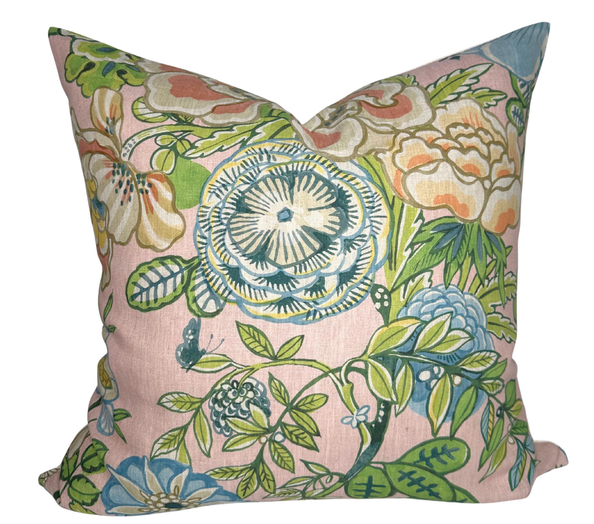 Square pillow cover with blush pink background featuring large, detailed floral patterns in green, blue, cream, and peach tones with leafy accents.