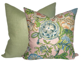 Two square pillows with removable covers, one in solid muted green textured fabric, the other in blush pink with a detailed botanical print in green, blue, and cream.
