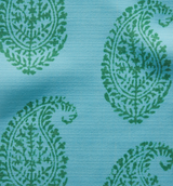 Green paisley motifs with floral details on a textured light blue fabric background, showing a close-up of textile weave and pattern repetition.