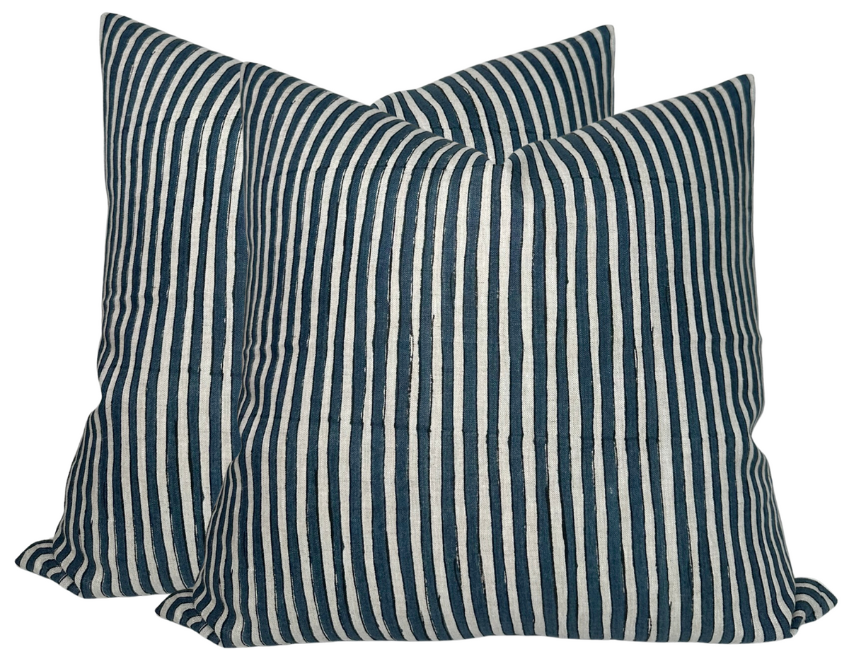 Two square pillow covers with narrow vertical stripes in Indian teal and off-white, showing a soft texture and slight creases on the fabric.
