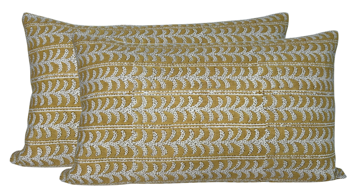 Two rectangular saffron pillow covers with horizontal white vine patterns repeating across their fabric.
