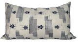 Yamato Pillow Cover in Blue laying on a sofa showing its blue printed front and ivory linen back