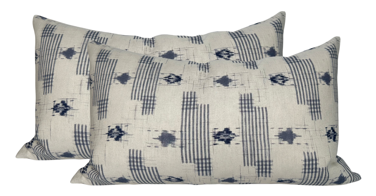Two rectangular pillows with a cream background featuring vertical dark blue striped and geometric patterns.