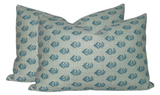 Two rectangular pillow covers with repeating blue floral motifs on a light beige woven fabric, arranged overlapping against a white background.