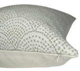 Close-up of a natural-colored woven pillow cover featuring a scalloped pattern of small dots and a visible zipper along the bottom edge.