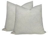 Two square natural-colored woven pillow covers with subtle inverse scalloped pattern and textured fabric shown against a white background.