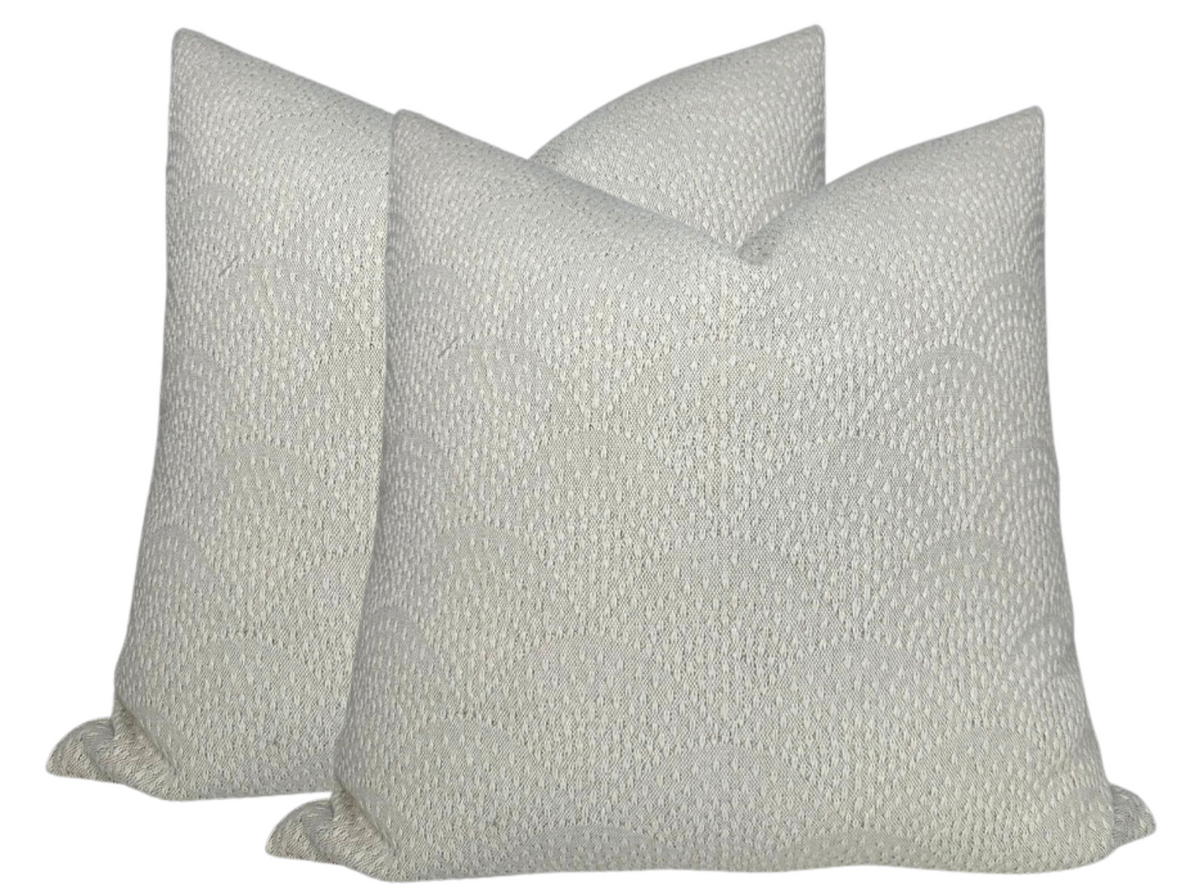 Two square natural-colored woven pillow covers with subtle inverse scalloped pattern and textured fabric shown against a white background.