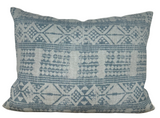 Rectangular pillow cover featuring a woven geometric pattern in muted blue and off-white tones with diamond and triangular shapes across its surface.