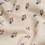 Beige fabric with a pattern of small stylized floral motifs, each featuring three red buds and blue leaves, shown with soft folds.