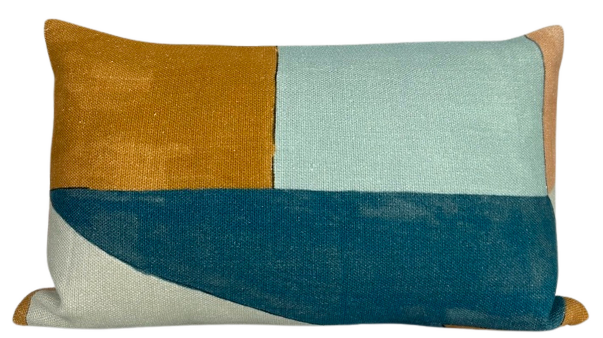 Rectangular pillow cover with a modern geometric patchwork of ochre, light blue, off-white, and deep teal fabric sections.