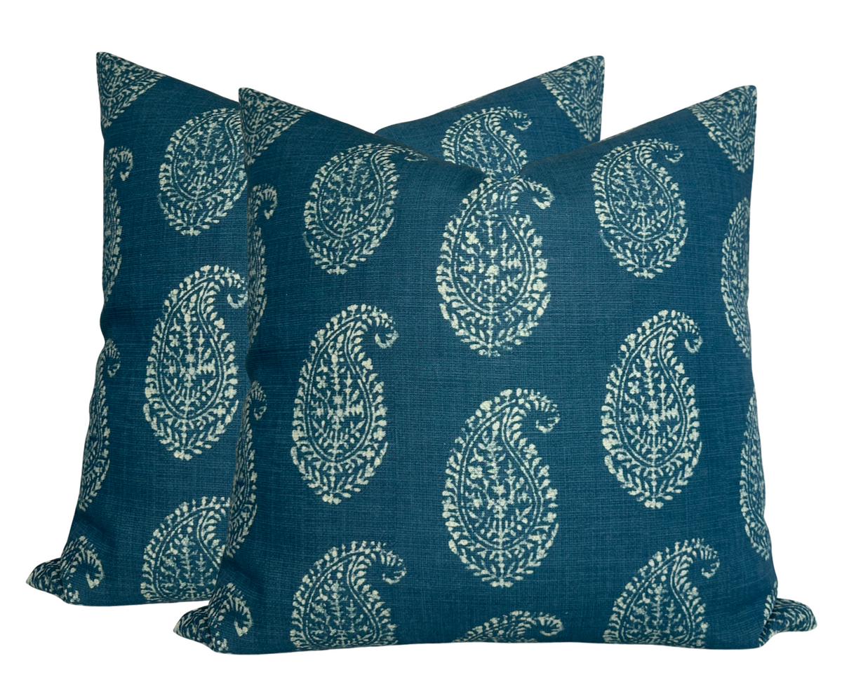 Two square pillows with an indigo blue background featuring a repeating white Kashmiri paisley floral pattern, made from textured fabric.