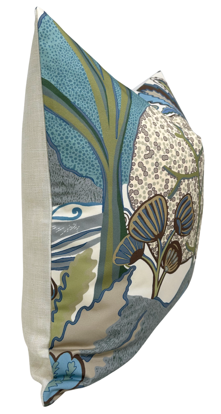 Square pillow with a beige linen side and a multicolored nature-inspired front featuring stylized trees, leaves, and berries in blue, green, and brown tones.