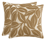 Two square pillows with mocha-colored abstract leaf patterns on a beige background, shown overlapping with soft texture visible.