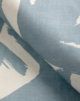 Close-up of a linen pillow cover featuring a bold abstract pattern with broad sky blue and off-white brushstroke-like shapes.