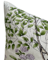 Close-up of a pillow cover featuring green leaves, thin branches, and small lavender flowers on a beige textured fabric background.