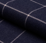 Close-up of navy blue wool fabric with a light beige grid pattern, showing texture and a soft fold.