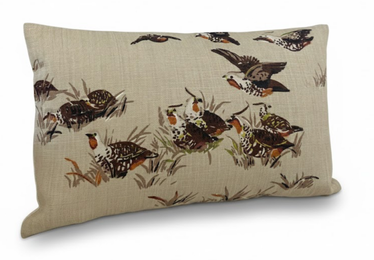 Rectangular tan brown pillow with detailed illustrations of small brown and white birds in flight and perched among grass on the fabric surface.