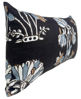 Rectangular pillow with black background featuring large lily floral print in white, blue, and brown tones, shown at an angle highlighting its soft texture.