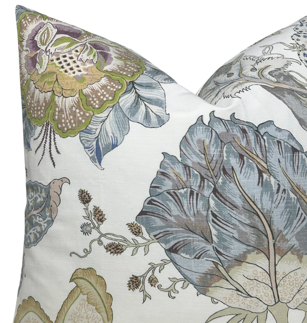 Close-up of a pillow cover with large floral patterns in muted blue, green, purple, and tan on a white background, showing detailed leaves and blossoming flowers.