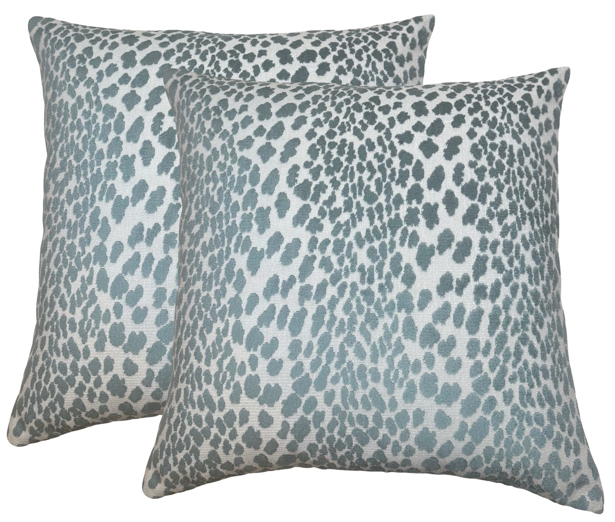 Two square velvet pillow covers featuring a scattered, irregular spotted pattern in marine blue on a light gray background, shown side by side.